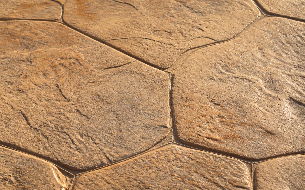 Close-up of decorative stamped concrete in warm sand tones with a natural stone pattern